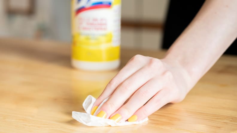 Hand wiping wood surface with Lysol wipe