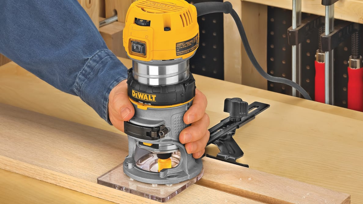 A person saws a plank of wood with the Dewalt DWP611 Compact Router.