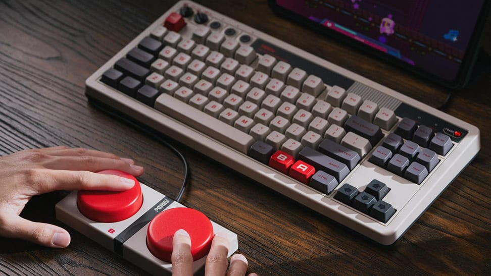 The 8BitDo Retro Mechanical Keyboard on a wooden table along with its Dual Super Buttons.