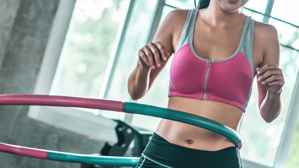 A woman using a hula hoop at the gym.