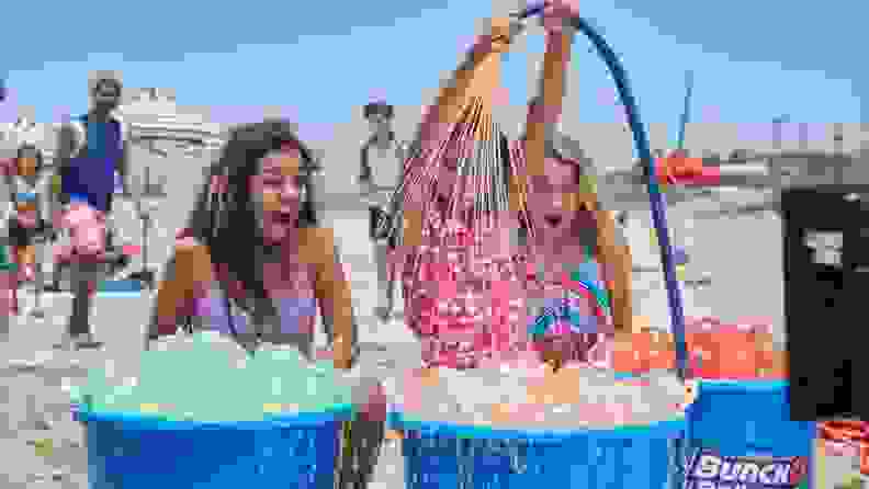 Three girls look on with excitement on buckets filled with full water balloons