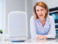 Person standing in kitchen talking to Amazon Alexa smart speaker.