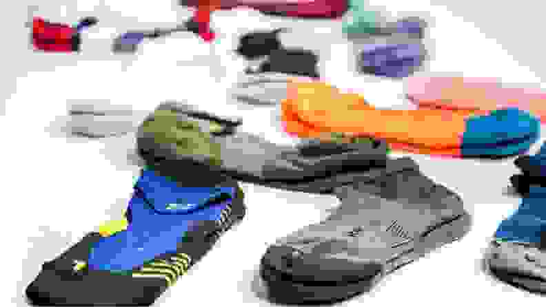 Pairs of running socks lying on the ground by brands like Nike, Saucony, Smartwool, Darn Tough, and more.