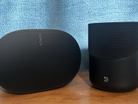The Sonos Era 300 and the Bluesound Pulse M home audio ecosystems placed side by side on a wooden surface.