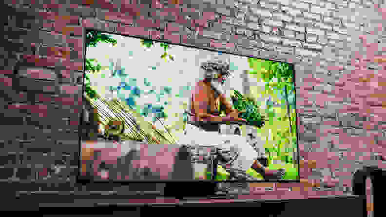 A muscular elder man sitting in a sunlit rainforest on the TV's screen