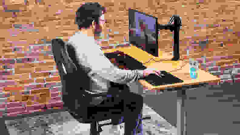 A person sitting on the Amazon Basics Racing/Gaming style office chair using a computer on a monitor.