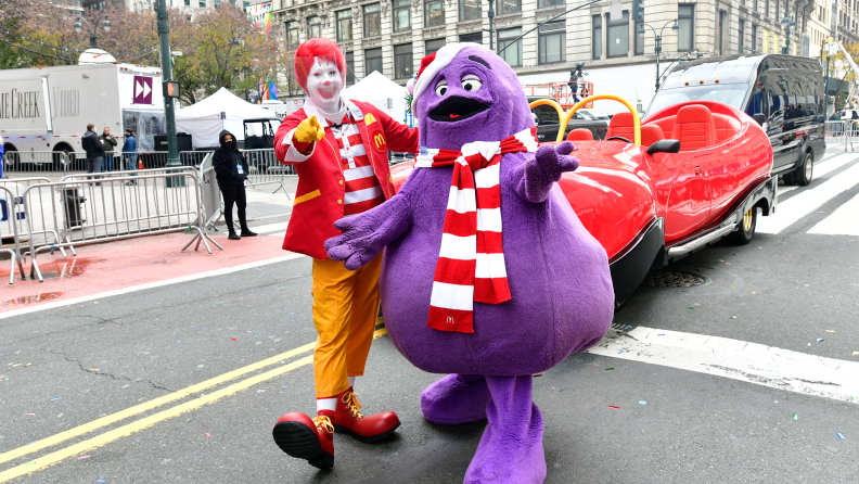 A photograph of Ronald McDonald and Grimace walking in a parade.