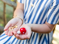 A pair of cupped hands holding a small felt mushroom and a small gold key
