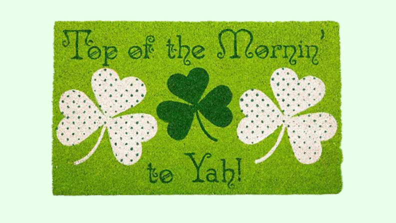 Green doormat with shamrock designs on front.