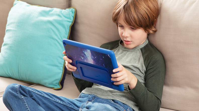 A kid sitting on the couch looking at a Fire 10 Pro.