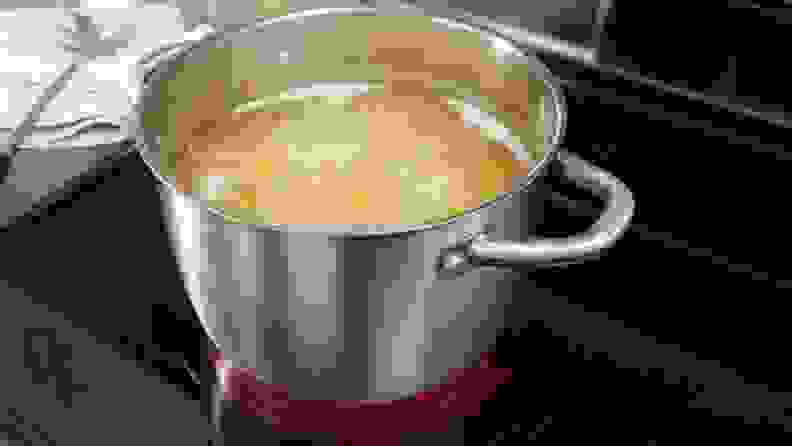 A large pot of water filled with pasta boils on an electric stovetop.
