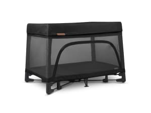 A small toddler sits on top of a patterned mattress inside of the Cosco Funsport Portable Compact Baby Playard.