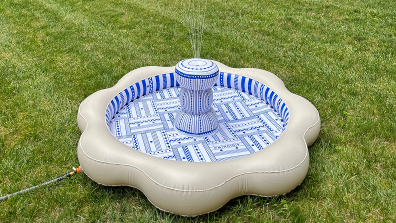 The Minnidip Luxe Inflatable Fountain spraying water outside on grass.