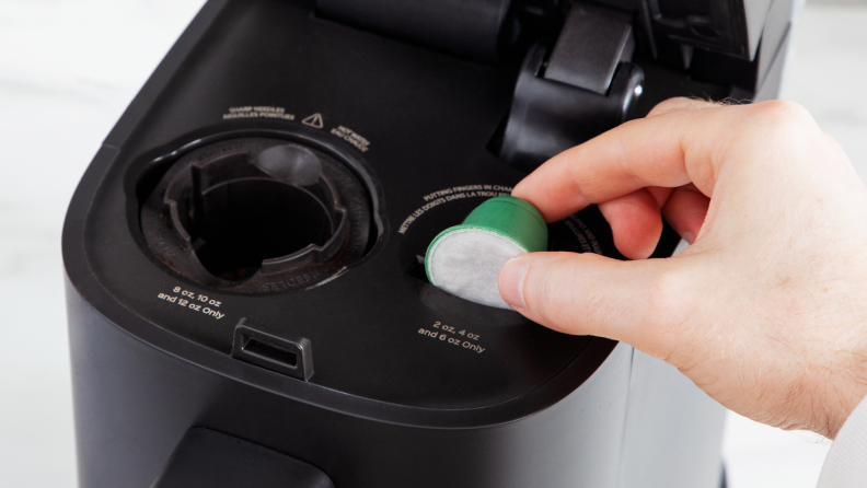 Person using finger to drop coffee pod into the chamber of the Instant Dual Pod Plus Coffee Maker.