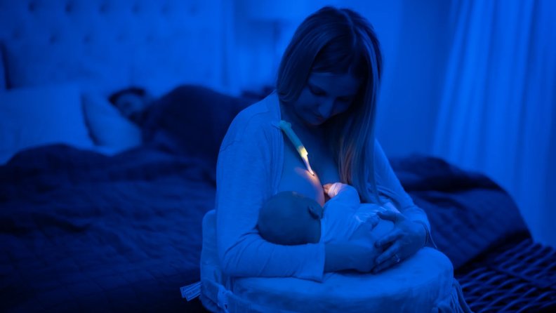 A woman breastfeeding a baby illuminated by the LatchLight