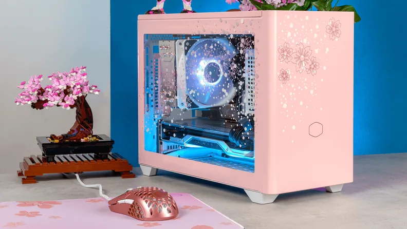 A small pink PC on a desk with a pink bonsai.