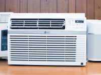 Three of the best window air conditioners are displayed on a wooden countertop, all are white.