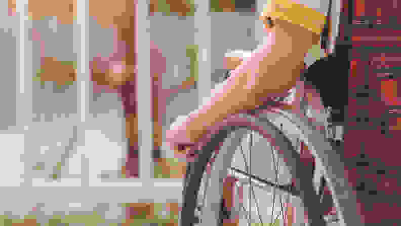 Person sitting in a wheelchair with one hand resting on the wheel.