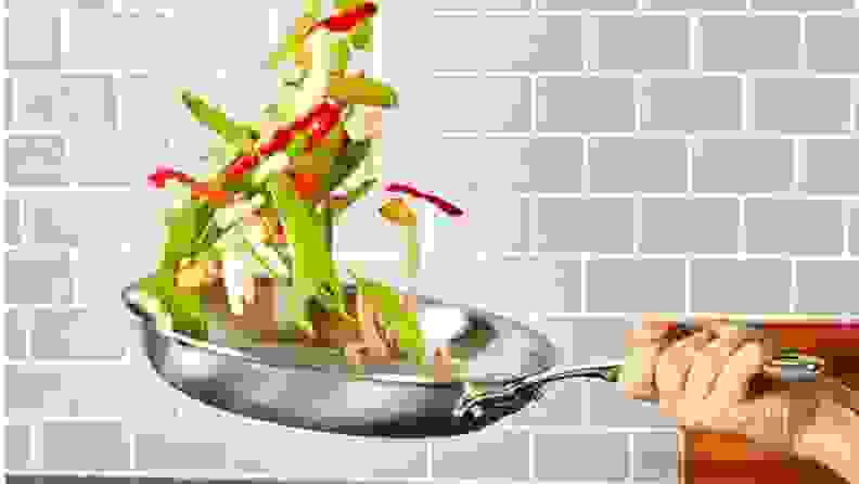 A chef tosses vegetables in a skillet.