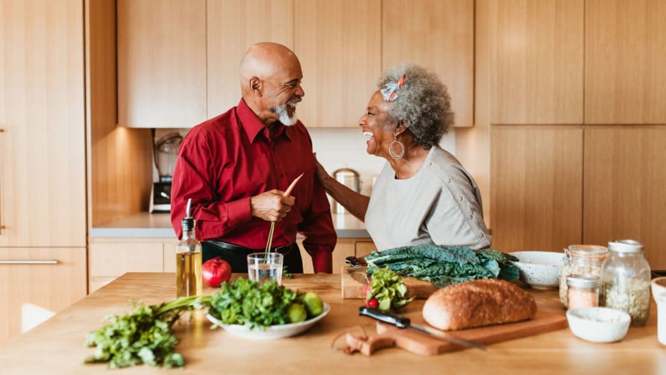 A couple laughs in their wood-paneled kitchen.