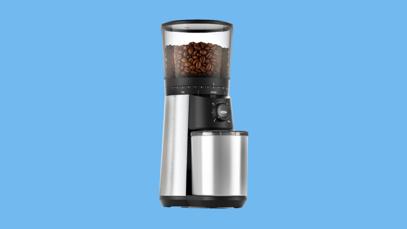 Coffee grinder with beans against blue background