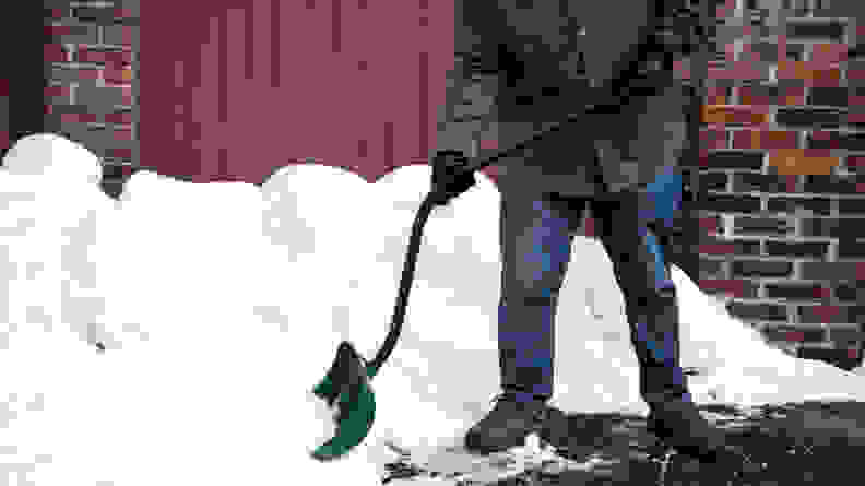 Person using a snow shovel on a large pile of snow.