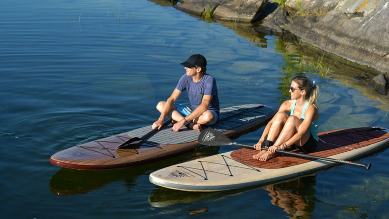 Two people sitting on paddleboards.