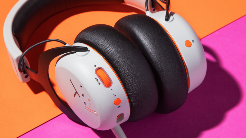 Looking at a white headset with orange knobs on a purple backdrop