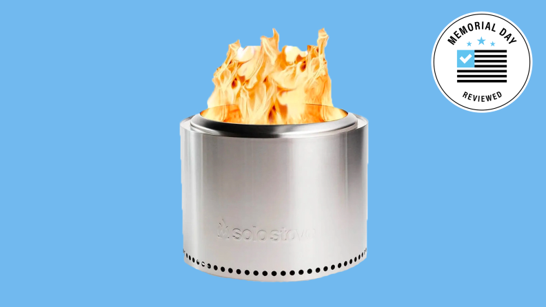 A Solo Stove with a fire going against a blue background.