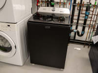 Black and silver Maytag MVW6500MBK top-loading washer inside of testing lab indoors.