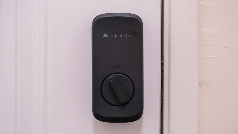 The Abode Lock shown hanging on a white door.