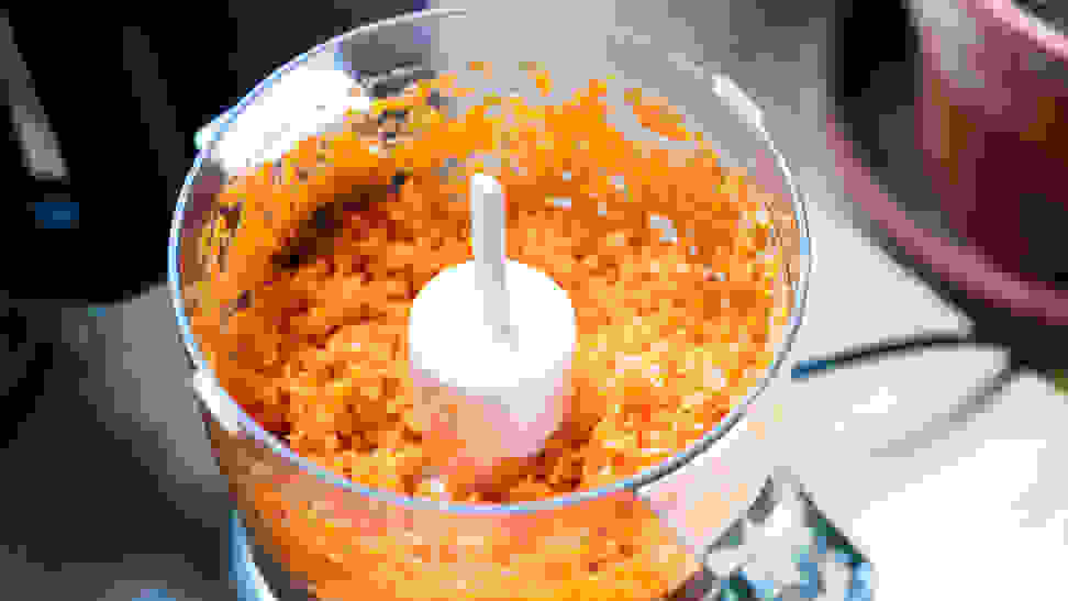 A Cuisinart mini food processor with its lid off and shredded carrots in the bowl.