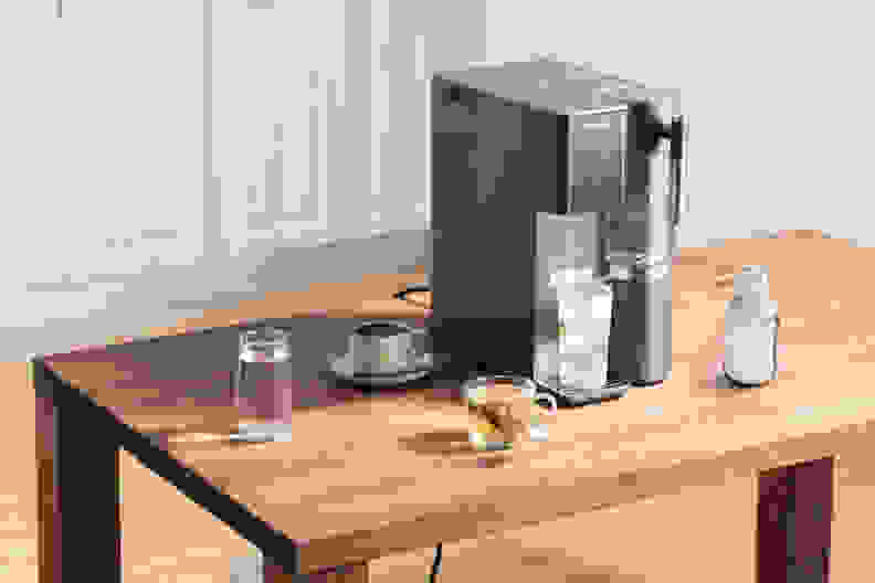 Black Waterdrop A2 reverse Osmosis system on a wooden table with cups of tea and coffee