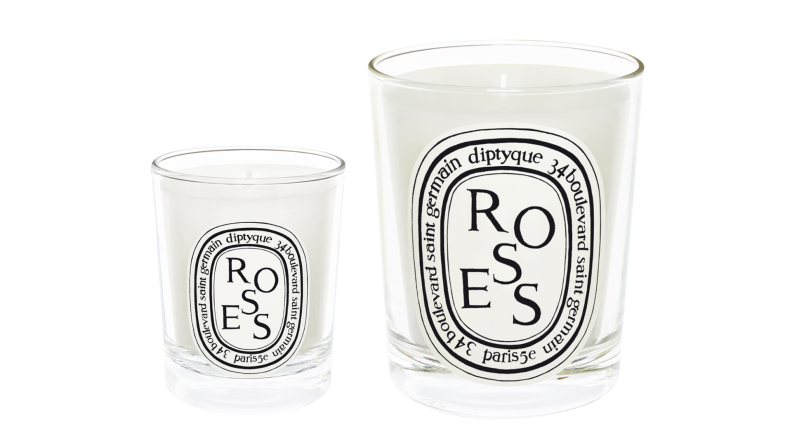 A small and medium sized rose-scented Diptyque candles against a white background.
