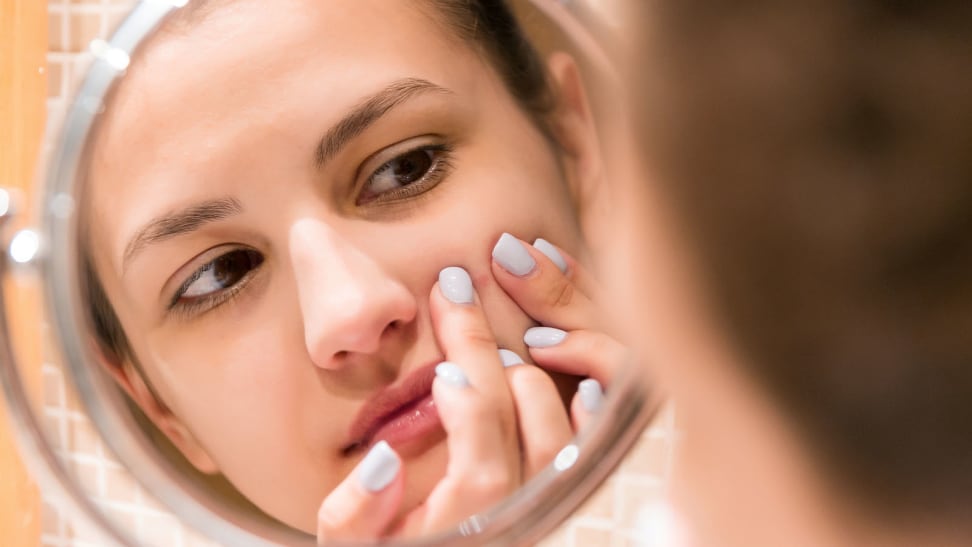 A woman popping a pimple on her face.