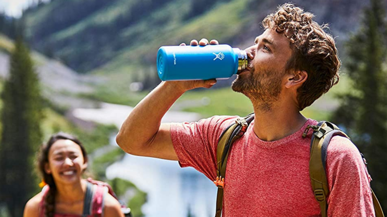 A person drinks from a Hydro Flask on a hike.