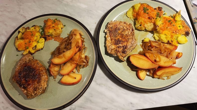 Two plates with porkchops, cooked apples and oven-roasted potatoes.
