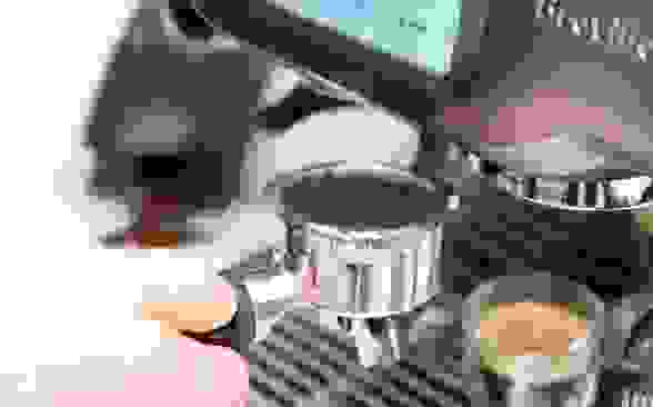 A person places espresso in an espresso machine
