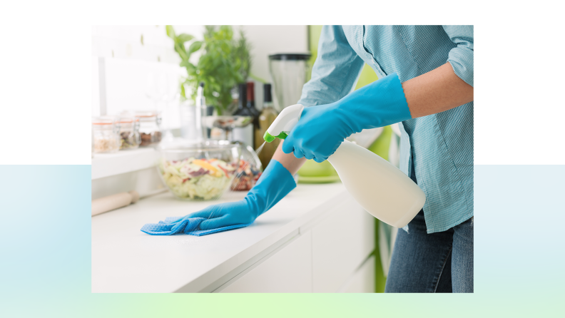 A pair of blue-gloved hands wipe down a kitchen counter.