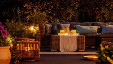Trendy outdoor patio furniture, lights, lanterns and candles in the garden at night.