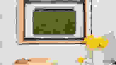 The July Air Conditioner, with its moss-covered panel, installed in a kitchen window.