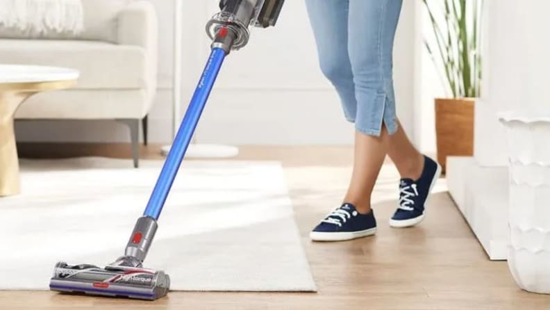 woman vacuuming white rug with Dyson vacuum