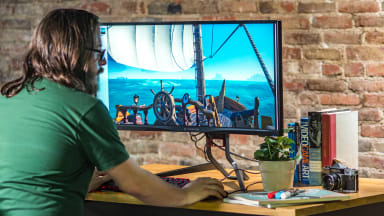 A man at a desk evaluating the best gaming monitors