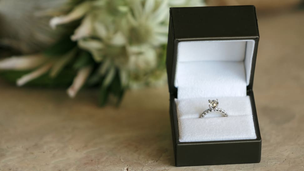 An engagement ring in a jewelry box on a wood table is the perfect kind of inspiration for buying an engagement ring.