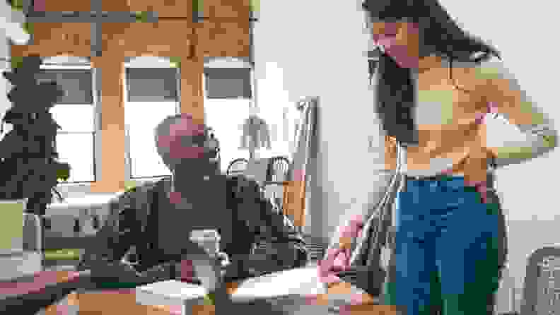 Two women stand over kitchen table and computer with tax documents