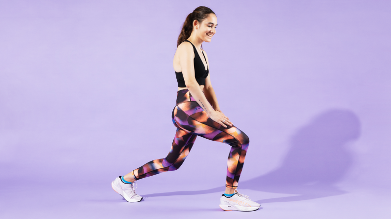 A woman lunging in Fabletics leggings.