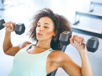 A woman using dumbbells for a chest press at the gym.