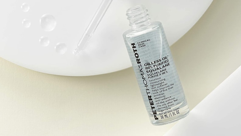 A clear dropper bottle of liquid laying with a dropper of liquid in the background.