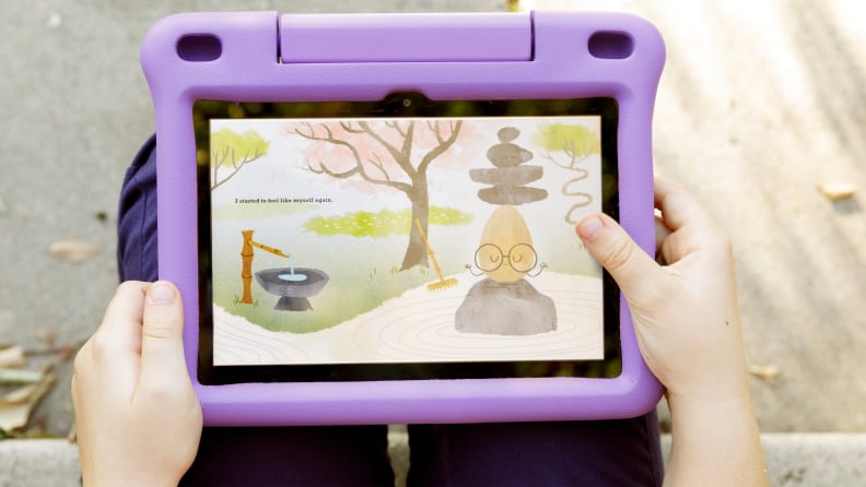 A child holding a kindle fire with a purple cover and an animation image on the screen.