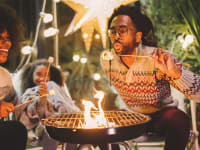 A family laughs around an outdoor fireplace